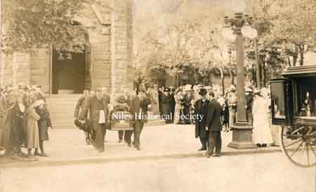 Postcard of typical funeral with pall-bearers exiting the Methodist Churchand placing the deceased into an awaiting horse-drawn hearse.