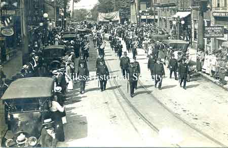 The "Blue Knights" of the Niles Police force, as shown here, were always at the head of many parades that were organized for every public occasion. Leading a parade down East State Street toward the curve from South Main Street.Picture circa 1915.