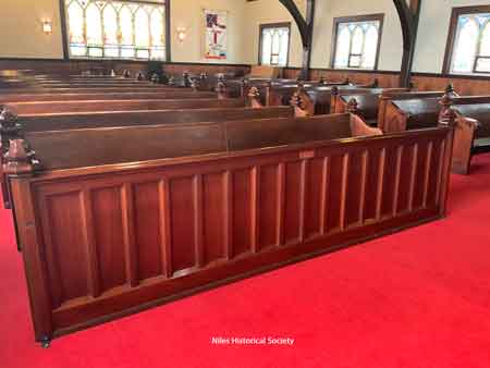 View of rows of pews and stained windows.