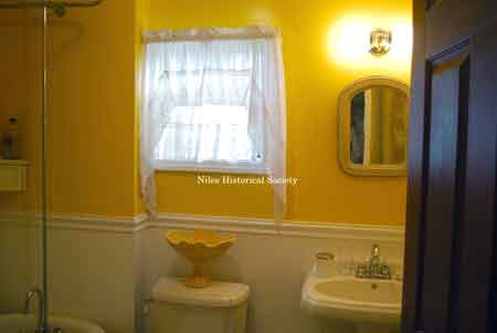 Detail of first floor bathroom showing porcelain sink and commode and wainscoting.