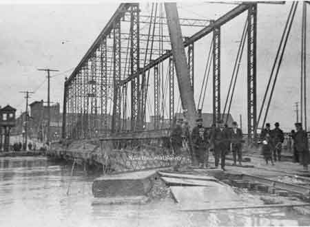 Bystanders on the Iron Bridge observing floodwaters.
