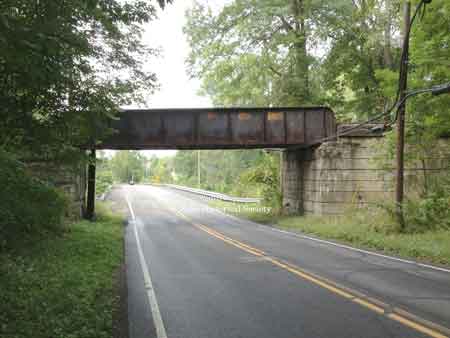 The steel girder railroad bridge that overpasses the roadway, West Park Avenue extension.